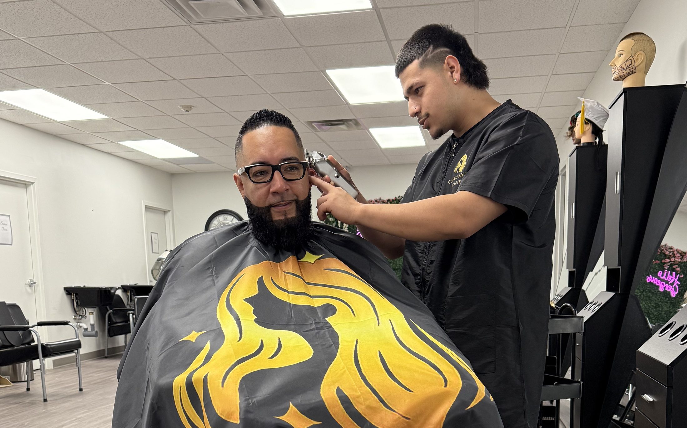 A Cosmo Beauty Academy barbering student giving a client a fade and beard trim in the barbering classroom in Saddle Brook, New Jersey