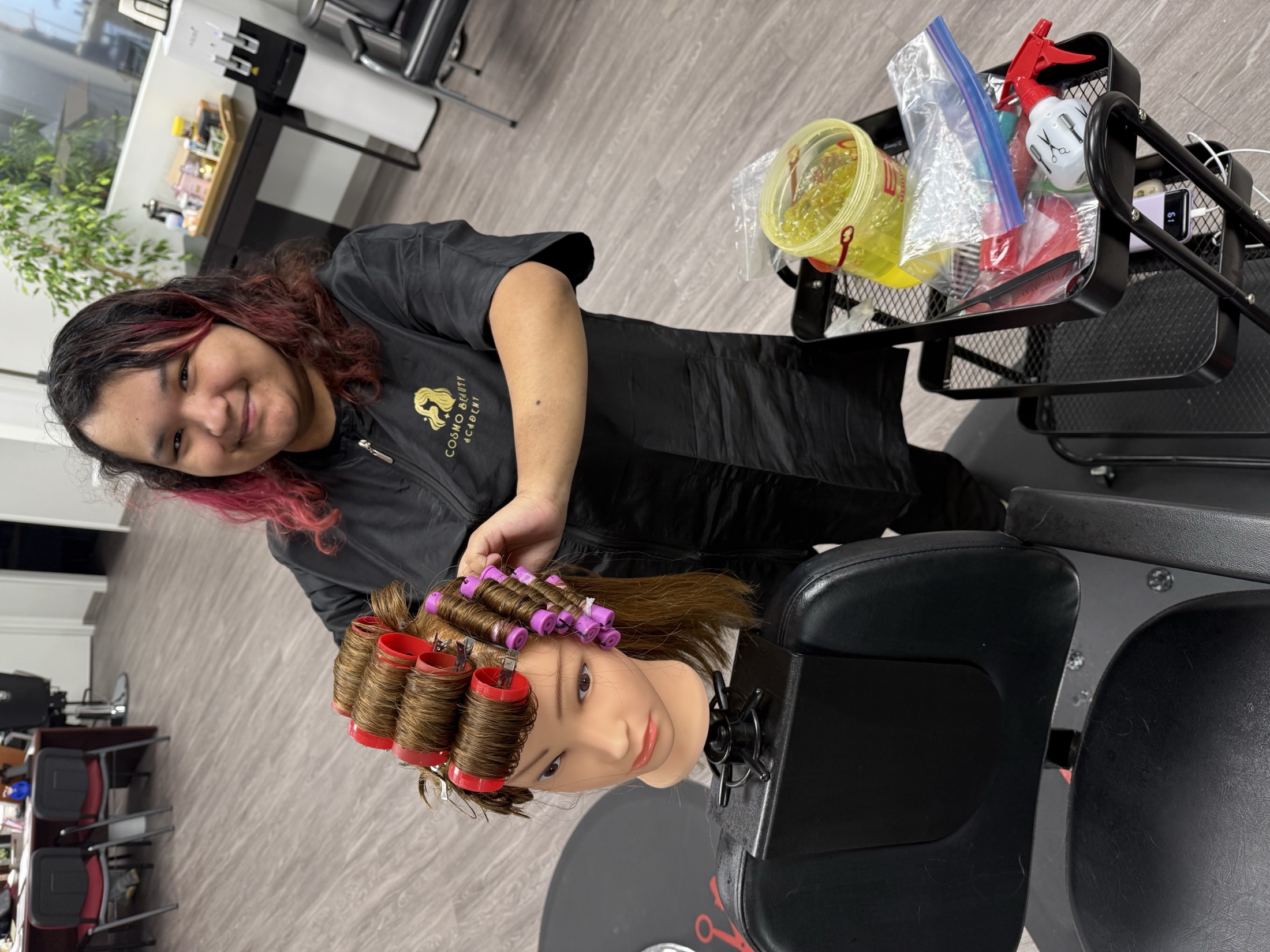 Cosmetology student setting hair rollers on a mannequin at Cosmo Beauty Academy in Saddle Brook, New Jersey